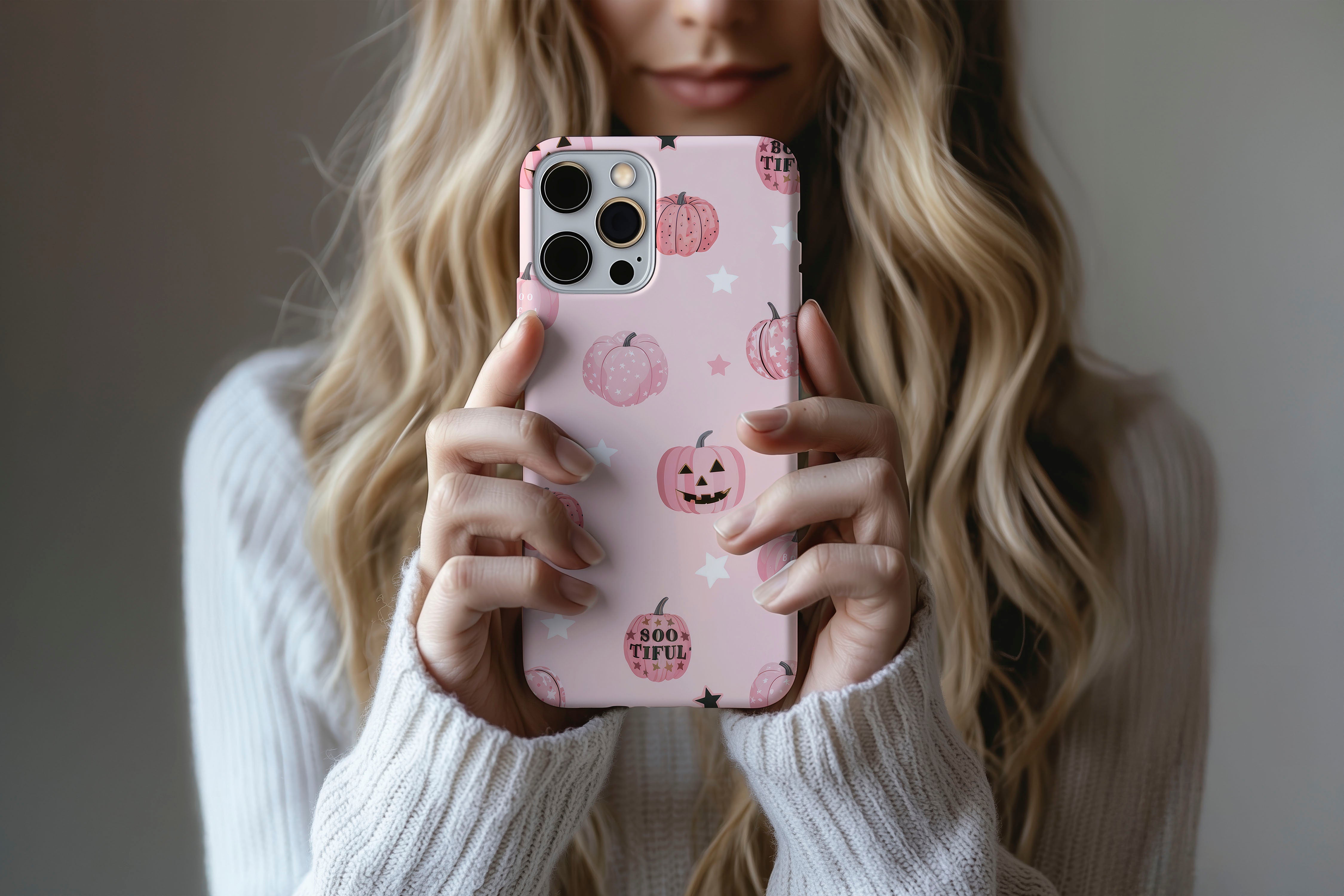 A cute girl holding a phone case featuring our Halloween Pumpkins design