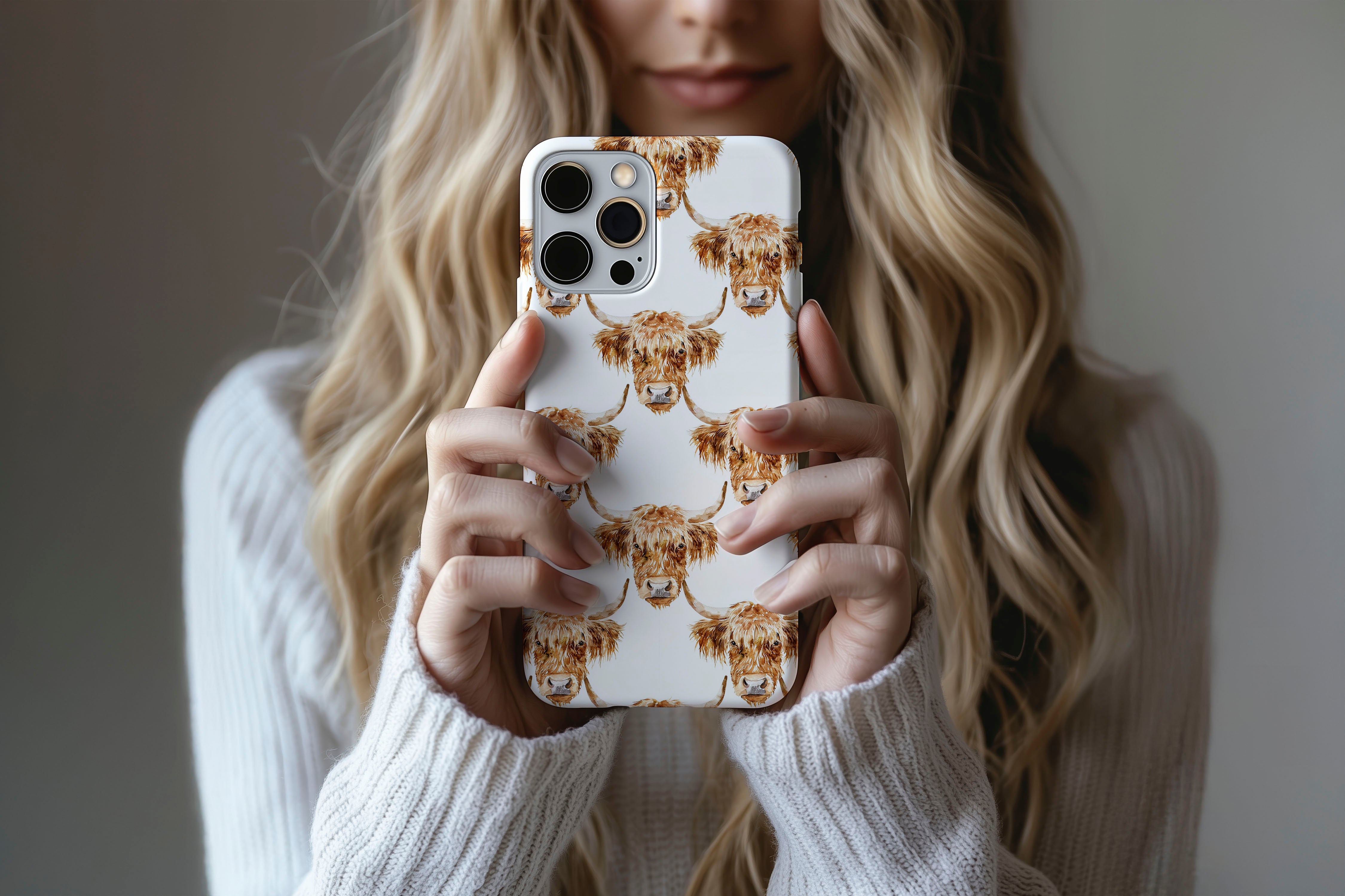 A cute girl holding a phone case featuring our Highland Cow design