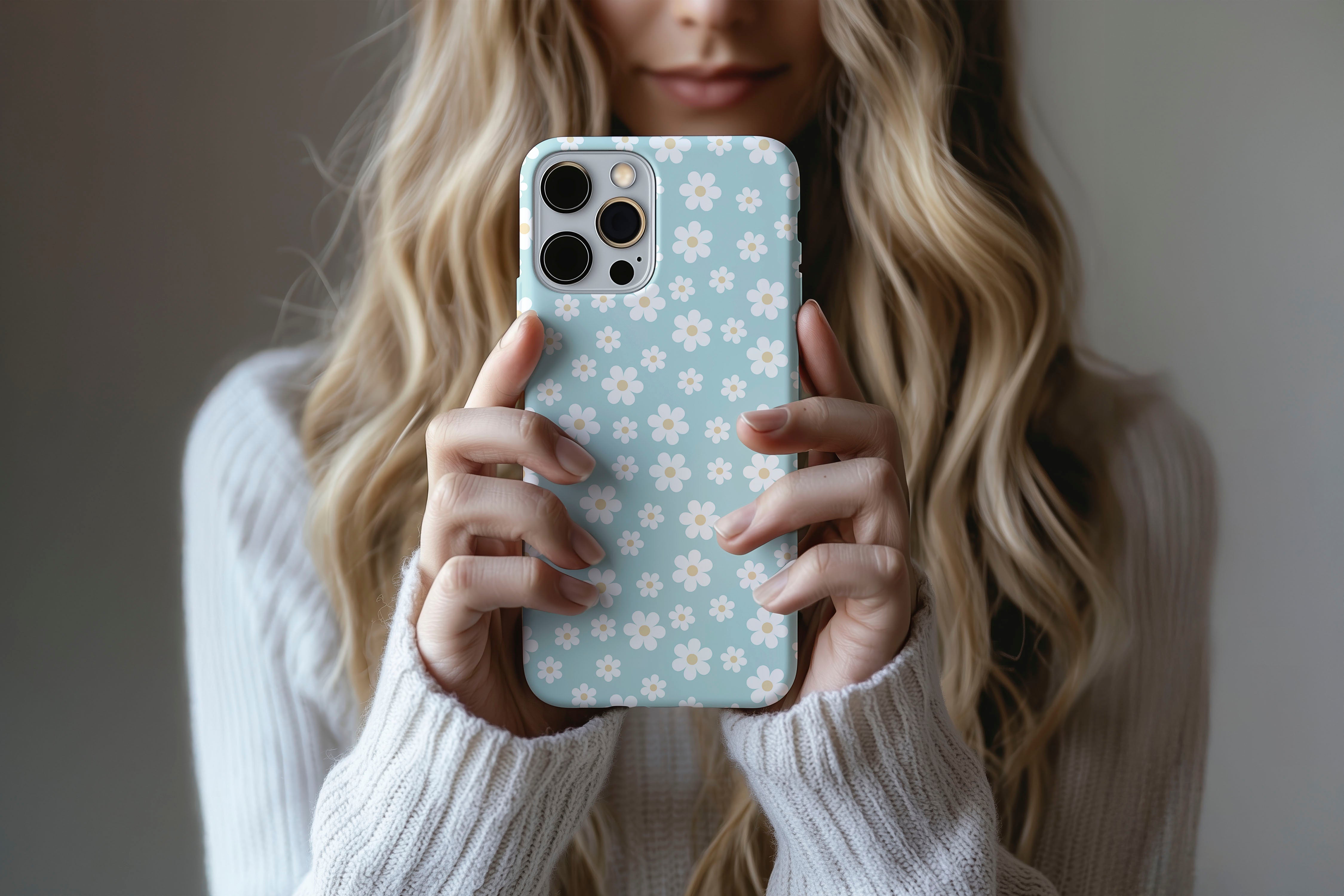 A cute girl holding a phone case featuring our Aqua Daisy design